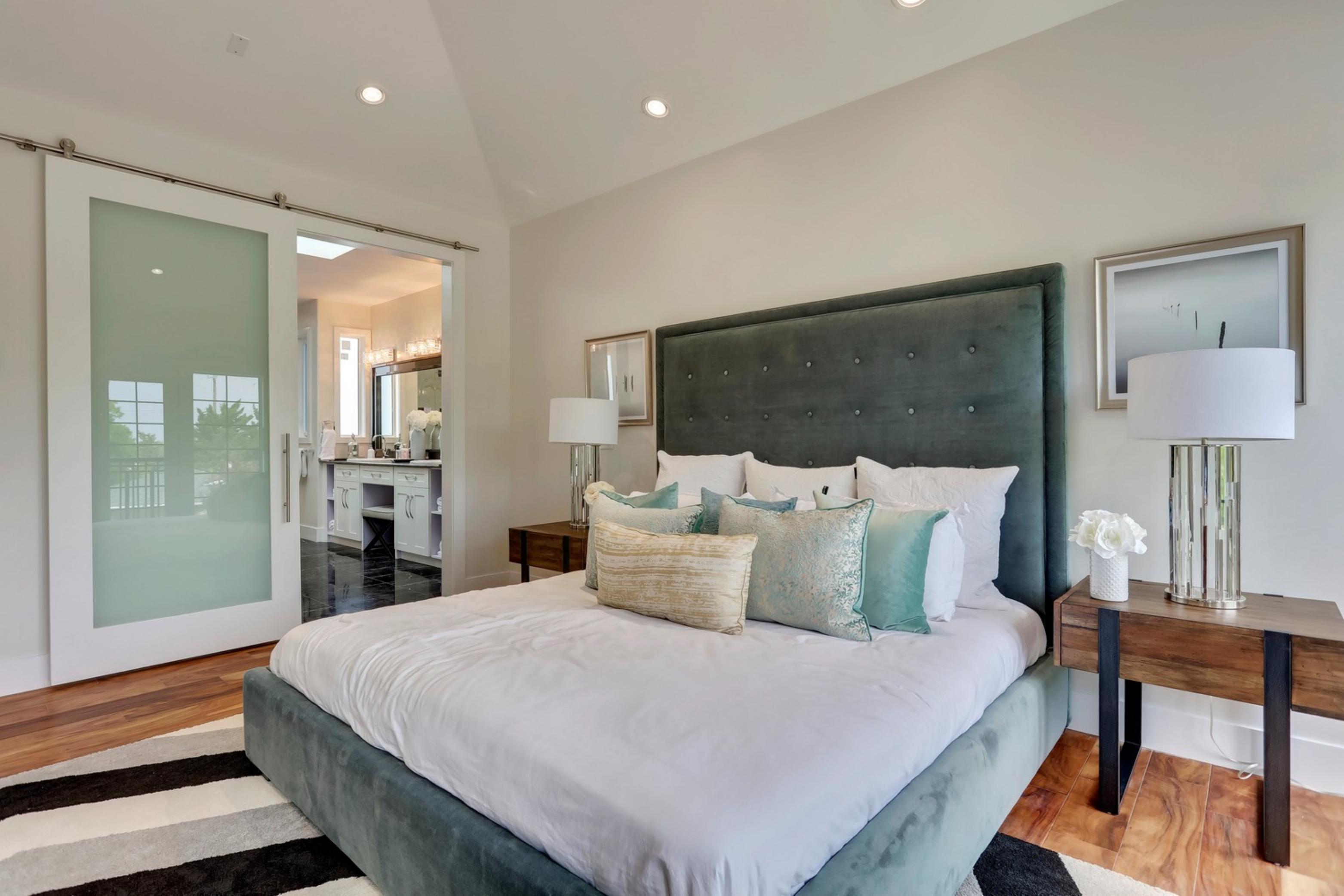 Killarney Custom Residence primary bedroom with tufted headboard and barn door to ensuite